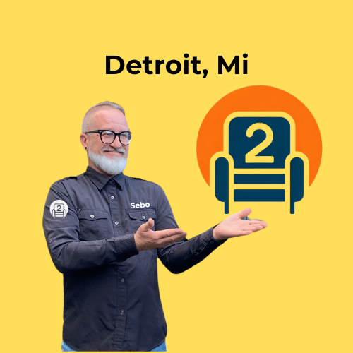 Sebastian gesturing toward the Number2project recliner logo with "Detroit, MI" displayed on a bright yellow background.