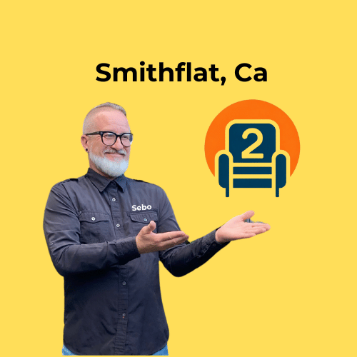 Sebastian, in a branded Number2project shirt, smiling and pointing toward a recliner logo with "Smithflat, CA" displayed on a yellow background.