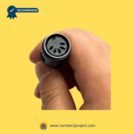 Close-up of a multi-pin connector for a massage recliner remote held in hand on a yellow background.